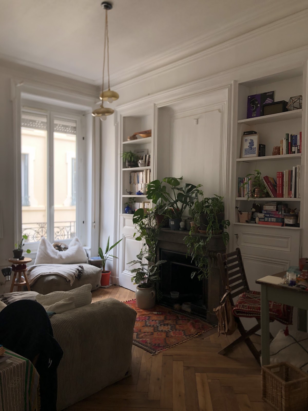Bibliothèques blanches encastrées de part et d'autre d'une cheminée ancienne, montées jusqu'à la corniche, dans un appartement haussmannien.
