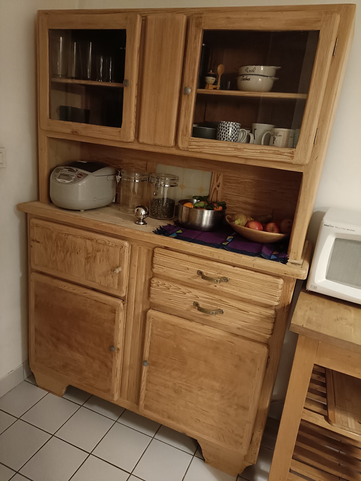 Vaisselier en pin clair à portes vitrées en partie haute, tiroirs et placards en partie basse, installé dans une cuisine.